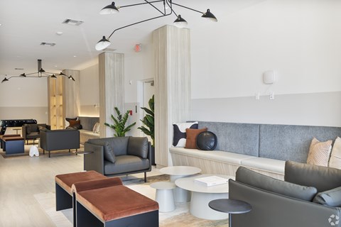 A modern living room with a grey couch, a brown leather ottoman, and a white sofa.
