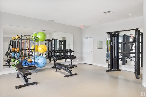A gym with a variety of equipment including weights and exercise balls.