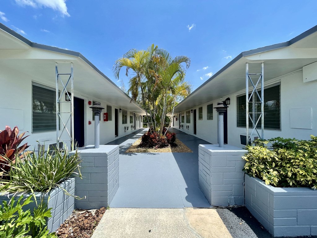 a courtyard with white buildings and a palm tree at Lakeside @ Biscayne Gardens,North Miami, FL,33181