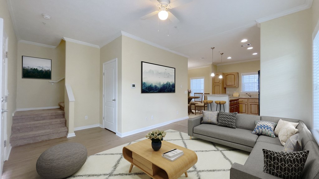 A living room with a grey couch, a coffee table, and a painting on the wall. A living room with a grey couch, a coffee table, and a painting on the wall.