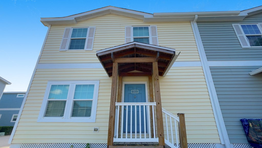 A yellow house with a white door and a balcony.