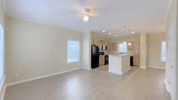 A spacious living room with a kitchenette in the background.