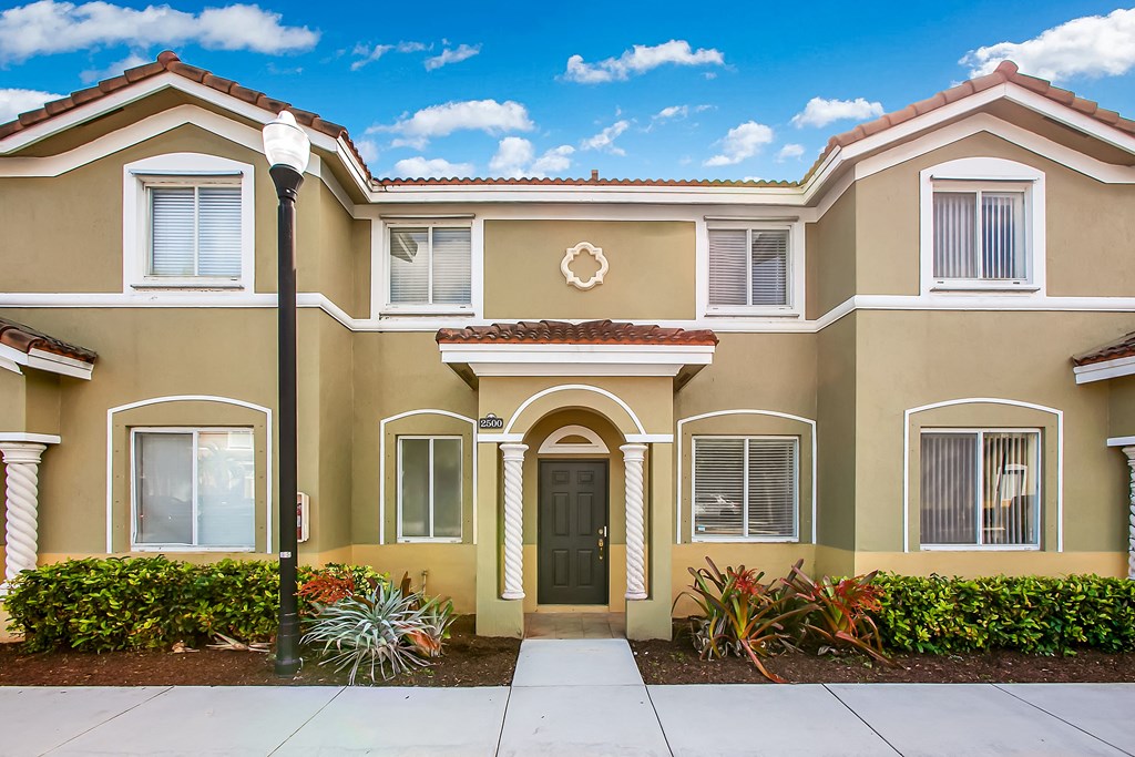 a beige house with a sidewalk in front of it