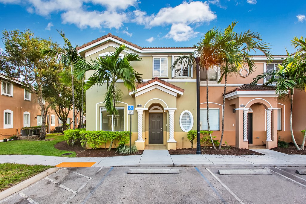 a house with palm trees and a sidewalk in front of it