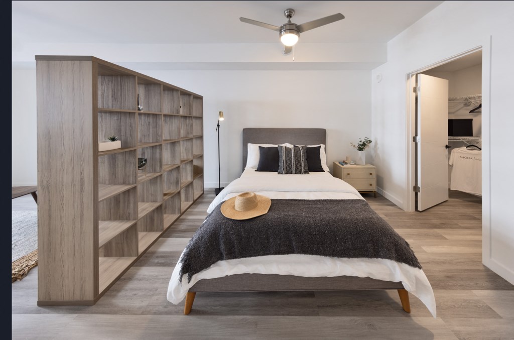 A bedroom with a large bed and a wooden bookshelf.