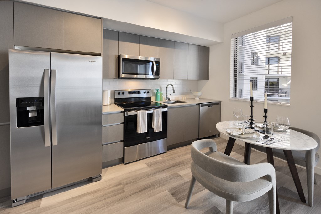 A modern kitchen with a stainless steel refrigerator and a round dining table.