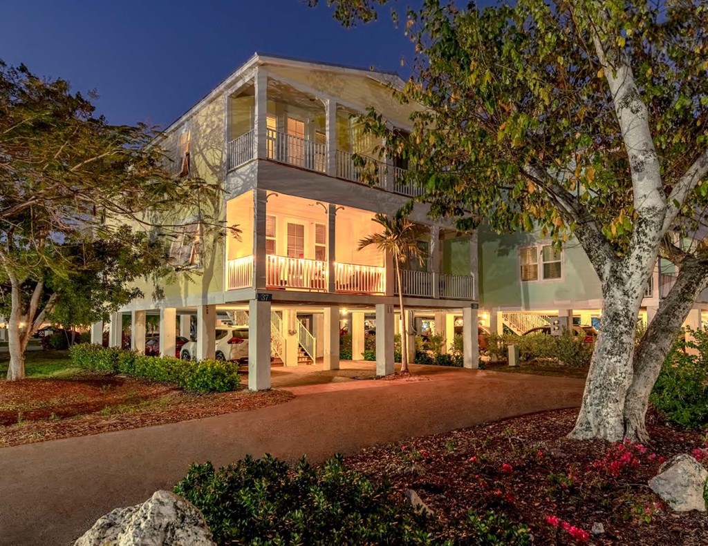A large house with a balcony and a tree in front.