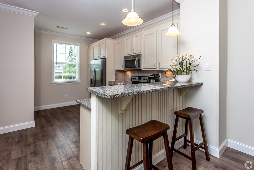 A kitchen with a granite countertop and wooden stools.