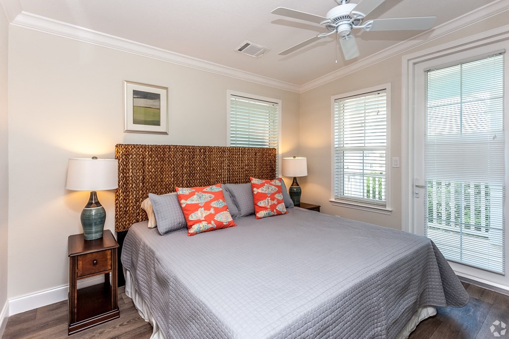 A bedroom with a bed, two lamps, and a ceiling fan.