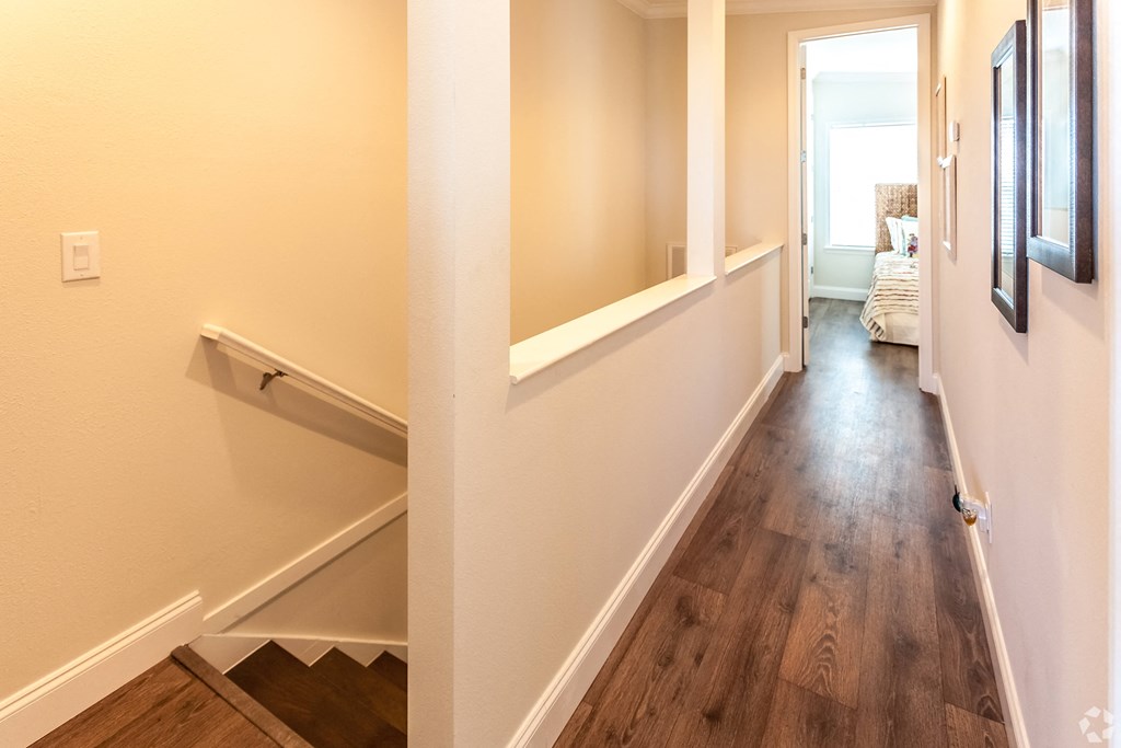 A hallway with wood floors and white walls.