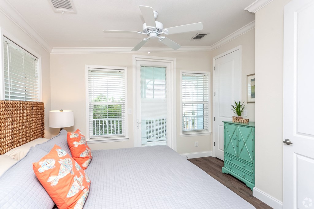 A bedroom with a bed, a dresser, and a window with blinds.