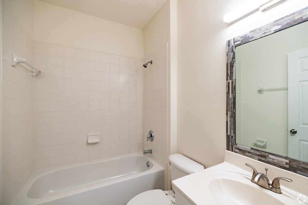 A white bathroom with a tub, toilet, and sink.