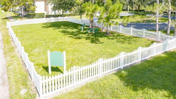 a white picket fence surrounds a yard with a lawn chair