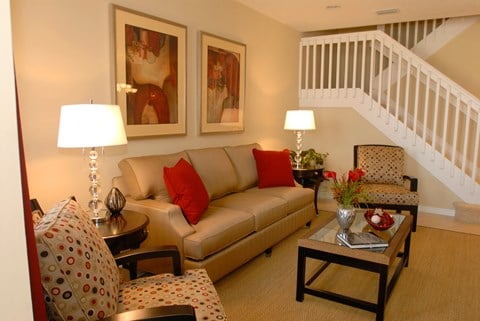 a living room with a couch and chairs and a staircase