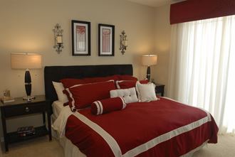 a bedroom with a bed with red comforter and pillows
