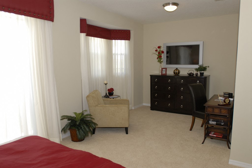 a bedroom with a bed and a chair and a dresser with a television