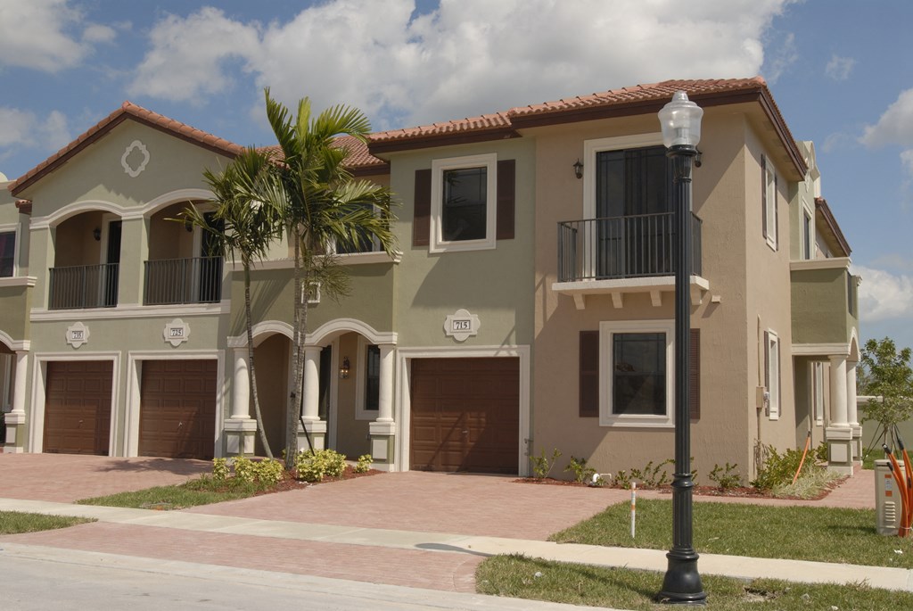 a house with three garages and a palm tree in front of it