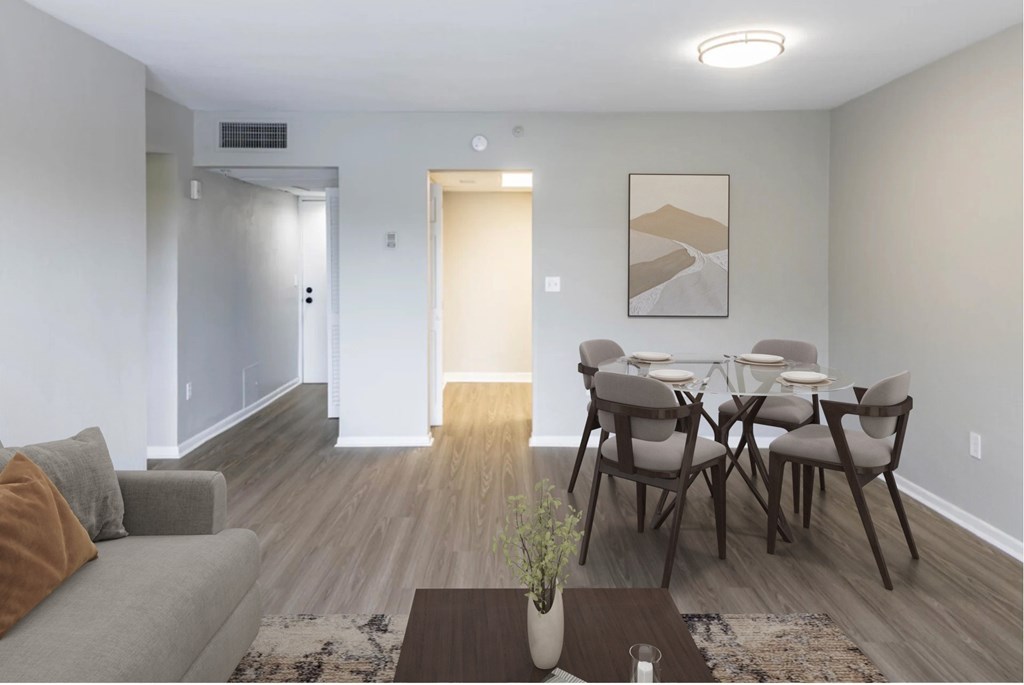 A modern living room with a grey couch, a coffee table, and a dining table set up.