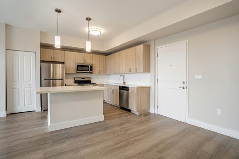 an empty kitchen with a large island and stainless steel appliances
