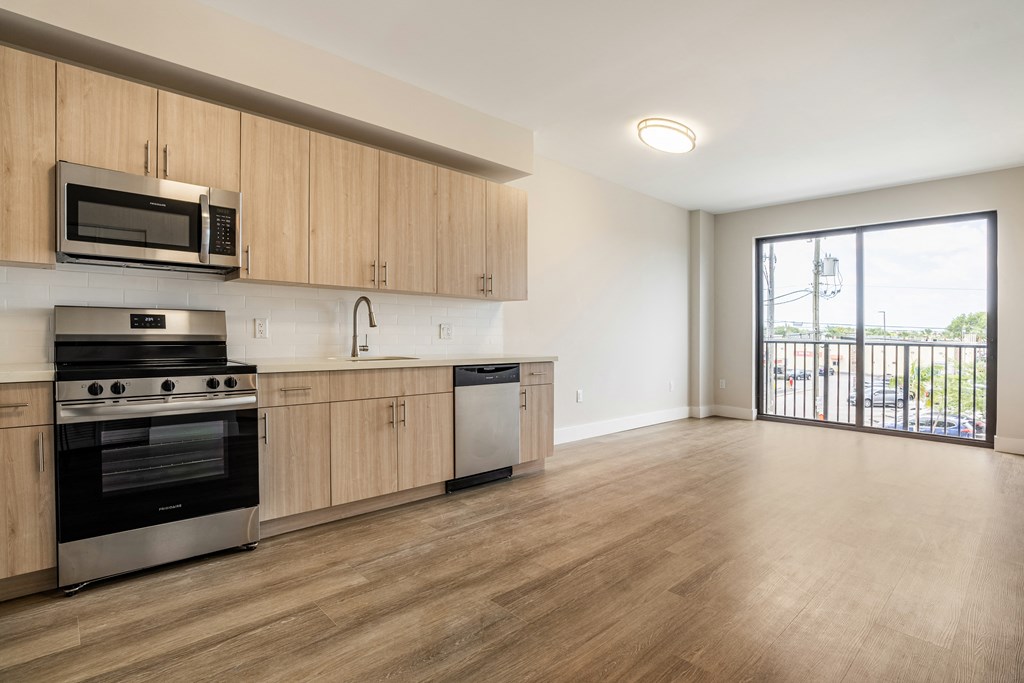 an empty kitchen with wooden cabinets and stainless steel appliances and a balcony
