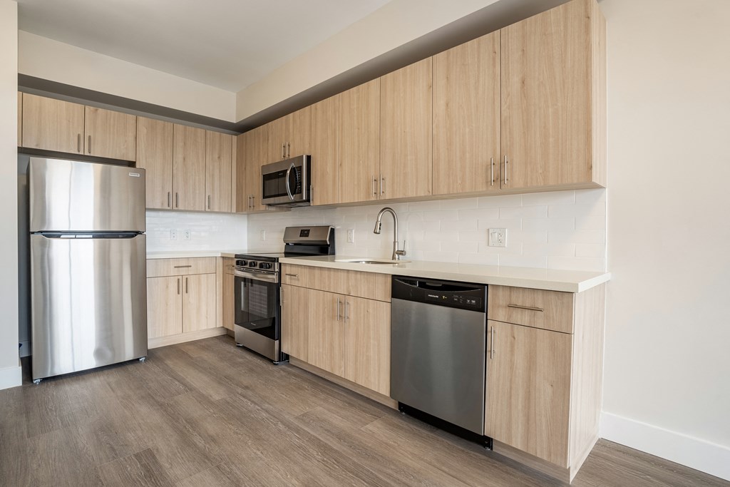 an empty kitchen with wooden cabinets and stainless steel appliances