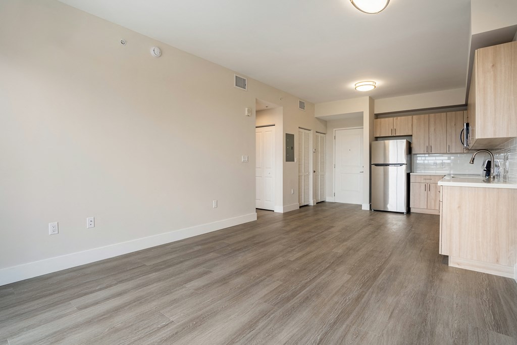 a kitchen and living room with wood flooring and a refrigerator