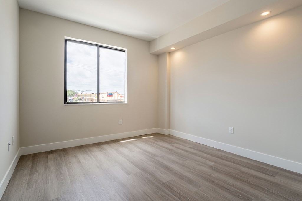 an empty room with wood floors and a window
