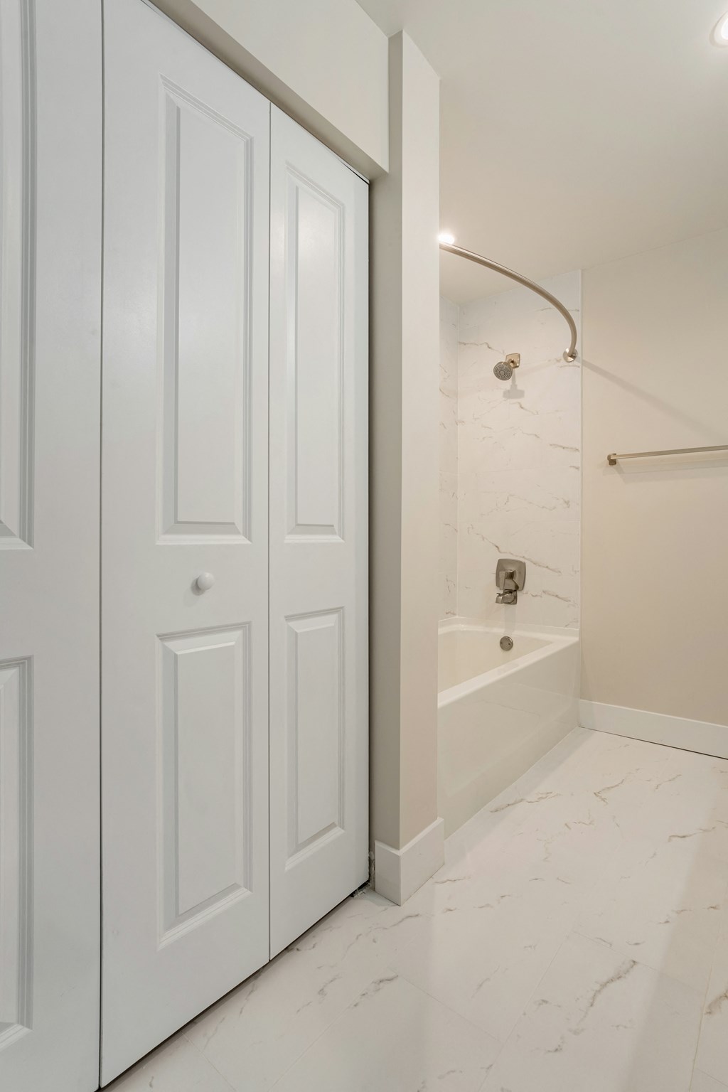a white door leading to a bathroom with a tub and shower