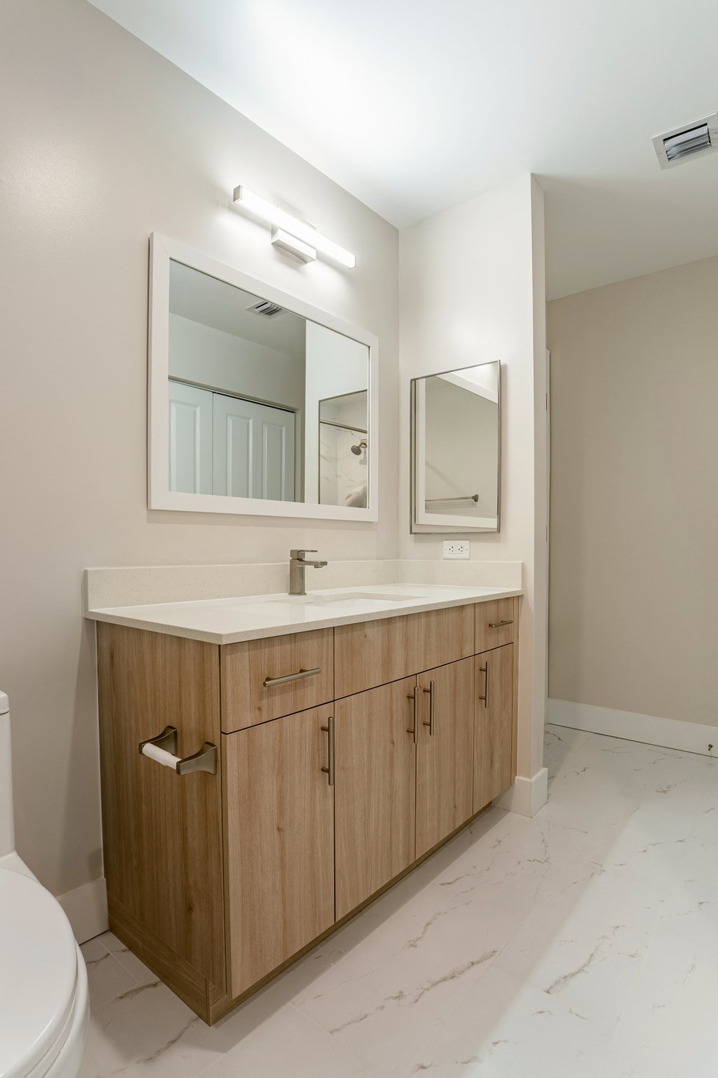 a bathroom with a wooden vanity with a mirror and a toilet