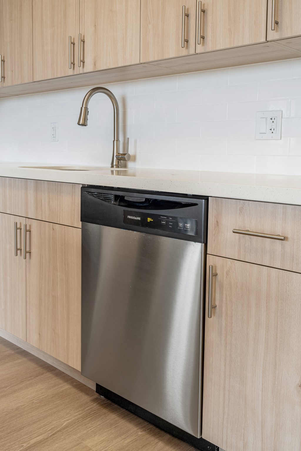 a stainless steel dishwasher in a kitchen with wooden cabinets