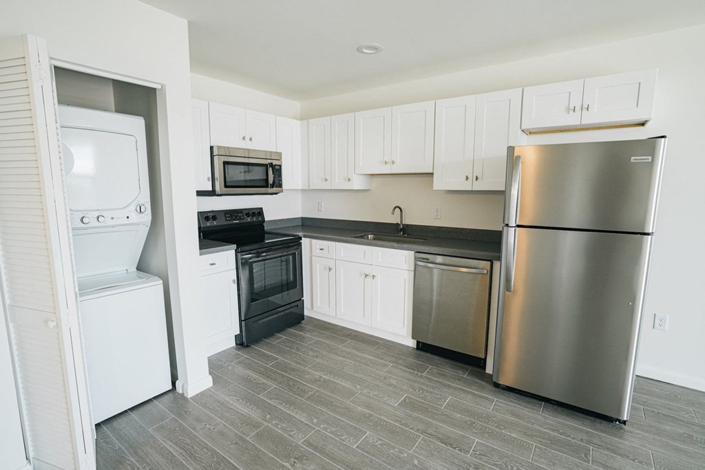A kitchen with a refrigerator, microwave, oven, and sink.