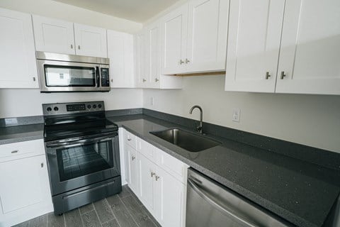 a kitchen with white cabinets and black counter tops and stainless steel appliances