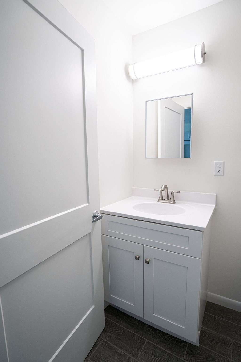A white bathroom with a sink and a mirror.