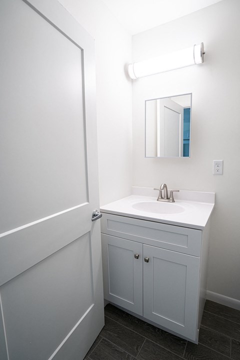 A white bathroom with a sink and a mirror.