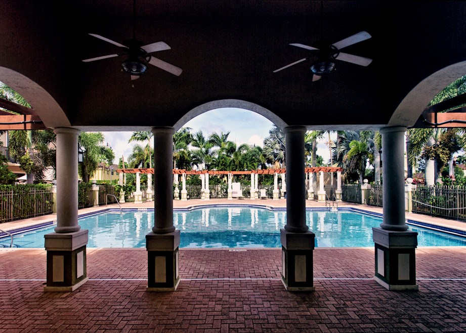 a large swimming pool in front of a building with ceiling fans