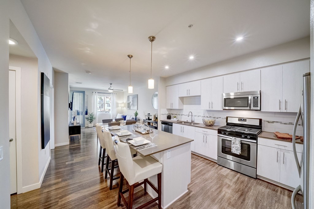 an open kitchen and dining area with white cabinets and stainless steel appliances