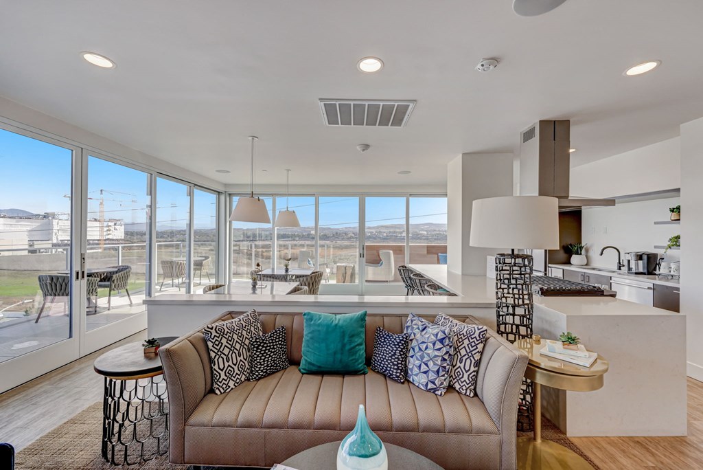 Living room with couch, kitchen view, and large window
