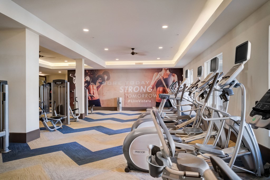 a gym with cardio equipment and weights on the floor
