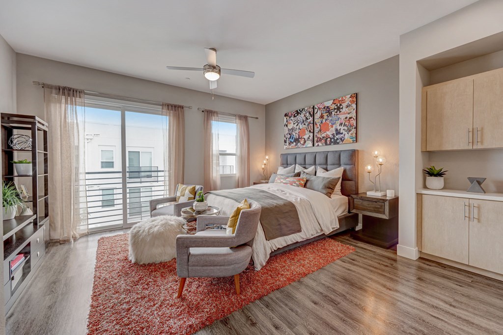 Bedroom with a bed, chair, red rug, and ceiling fan