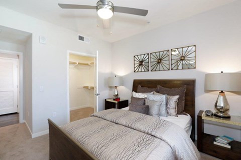 Modern bedroom with a bed and ceiling fan, offering comfort and style at Vistara Apartments