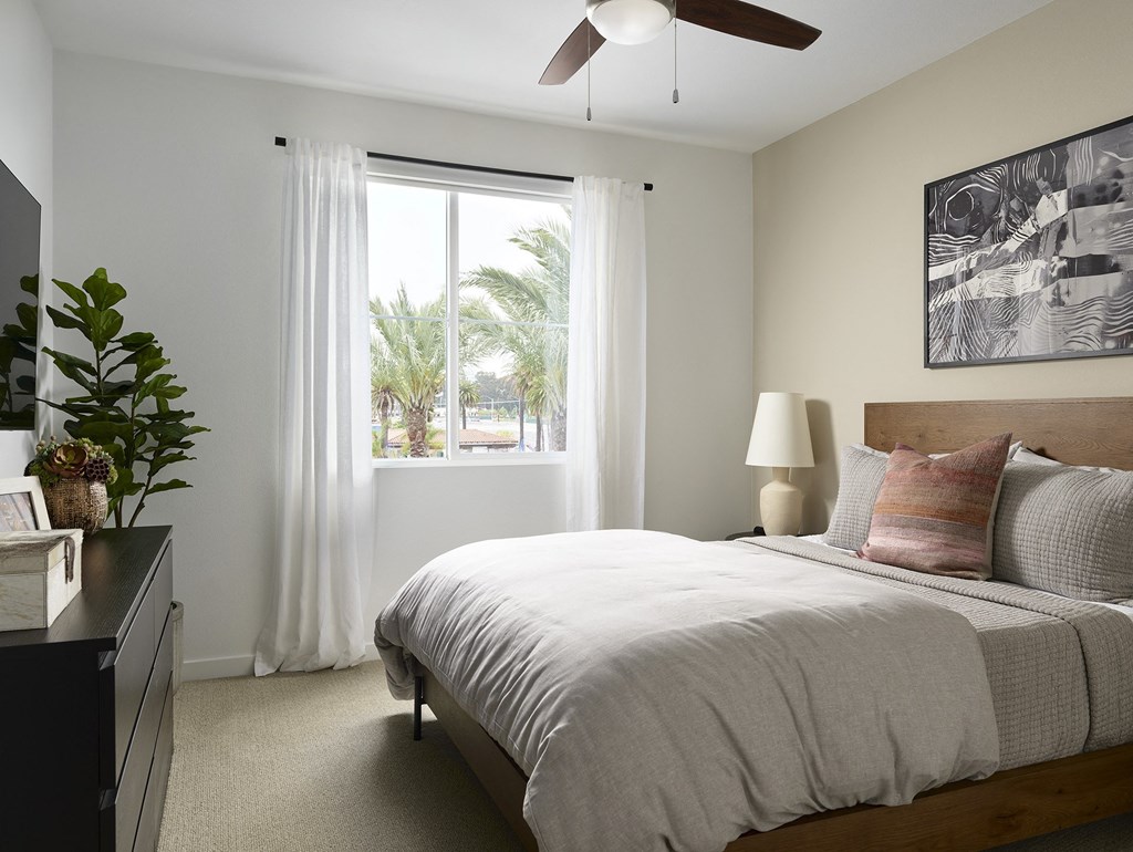 a bedroom with a bed and a window with white curtains