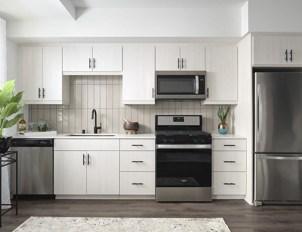 a white kitchen with stainless steel appliances and white cabinets