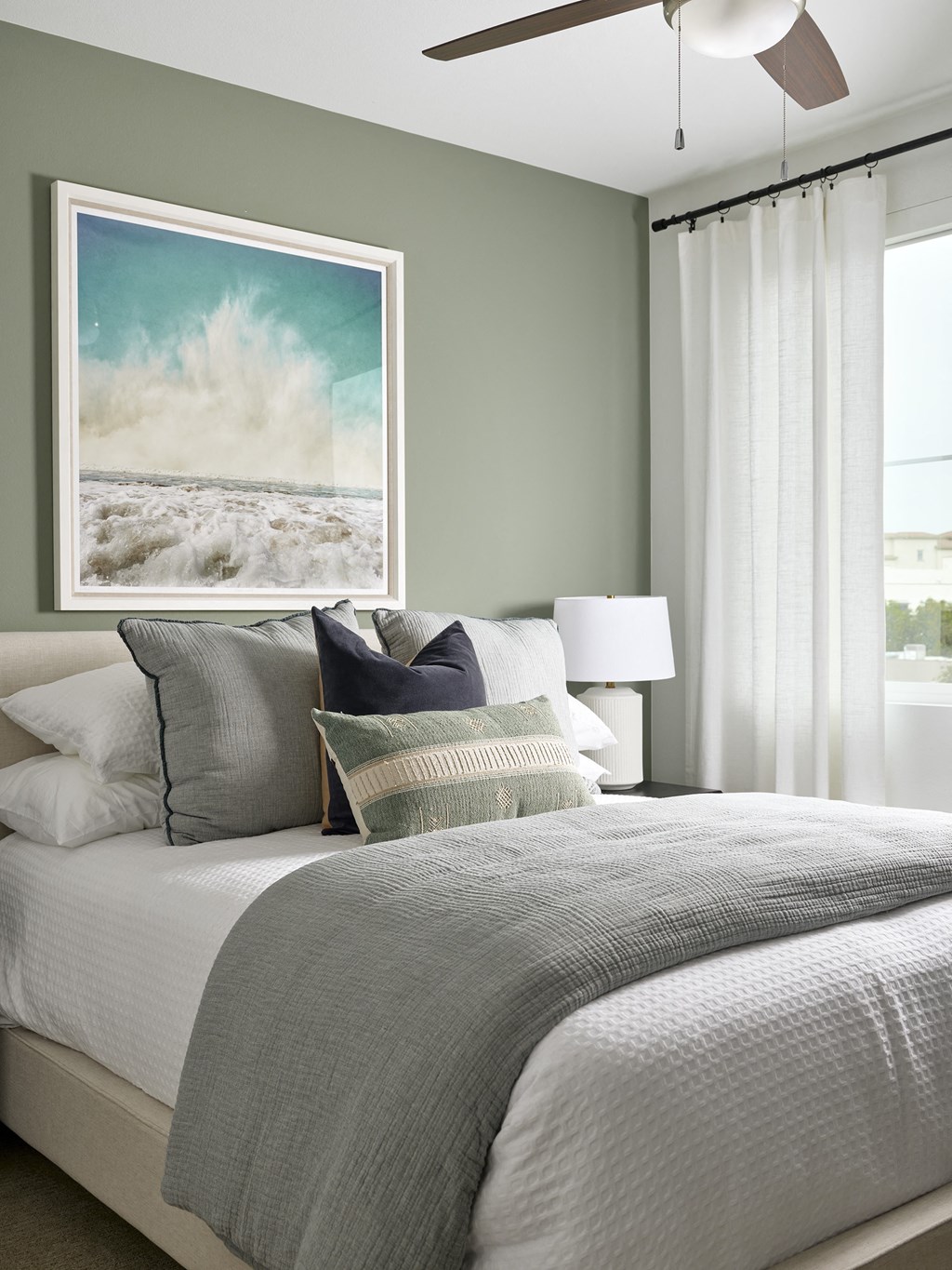 a bedroom with a bed with pillows and a painting on the wall above it