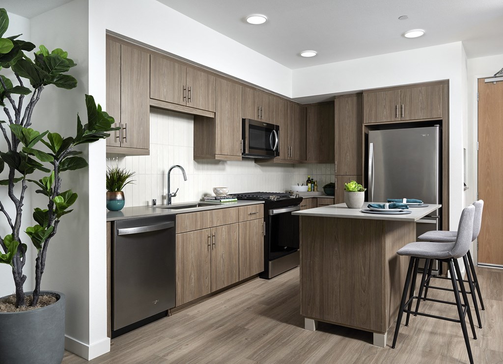 a kitchen with a large island and a stainless steel refrigerator