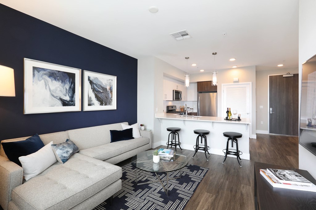 a living room with a couch and a coffee table in front of a kitchen