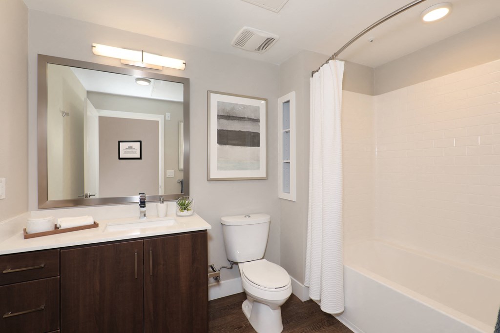 a bathroom with a toilet sink and mirror and a shower