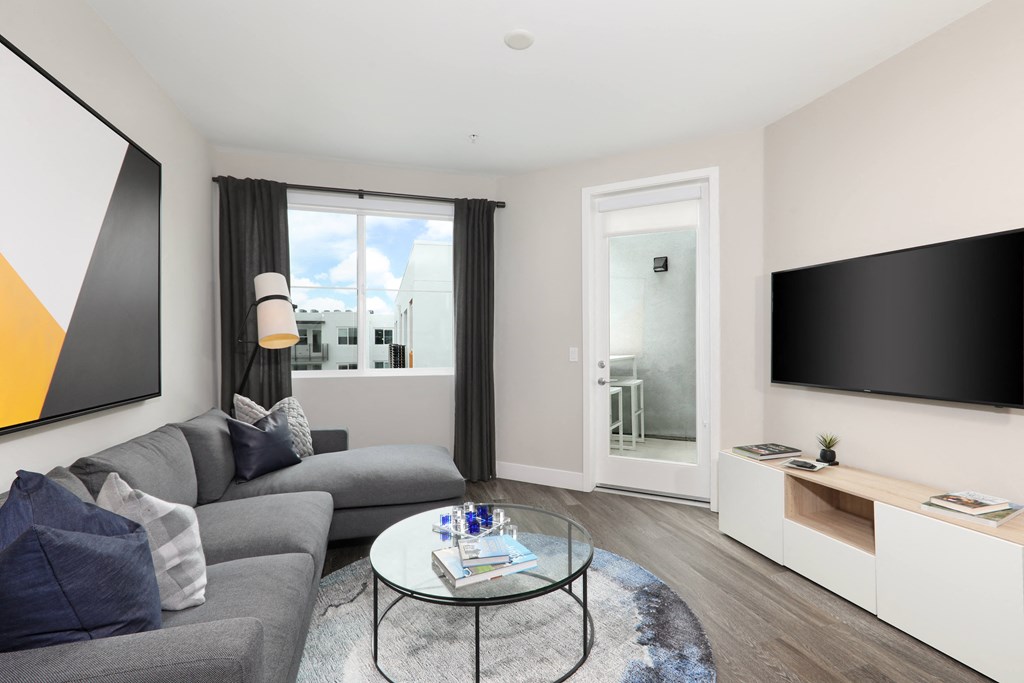 a living room with a gray couch and a coffee table and a television