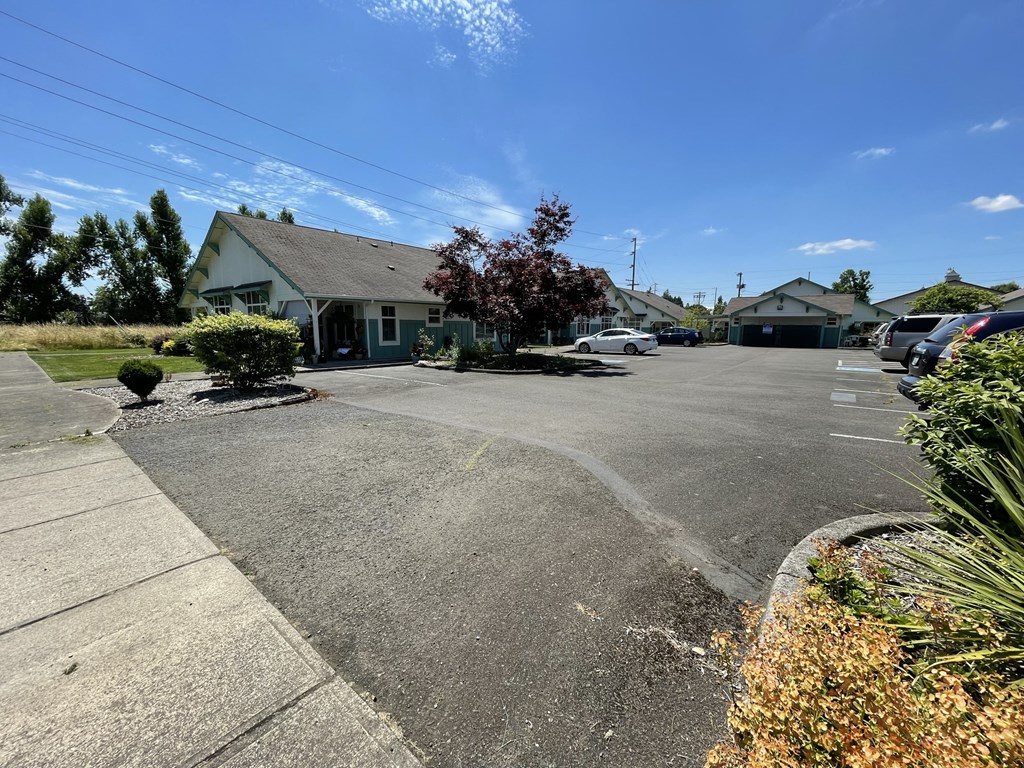 a street with houses and cars in a parking lot
