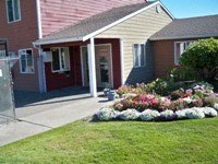 A house with a red door and a flower bed in front.