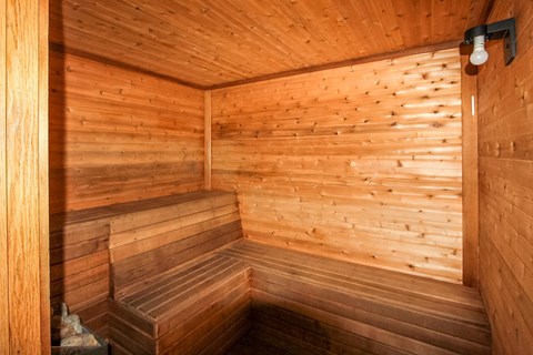 A wooden sauna with a bench and a light on the wall.